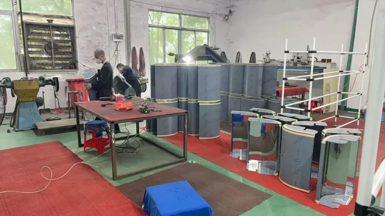 Two workers assembling machinery parts in a factory with tools and equipment on a table, surrounded by metal components and industrial machines.