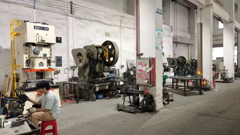 Worker operating machinery in a large industrial workshop with various machines and equipment visible.